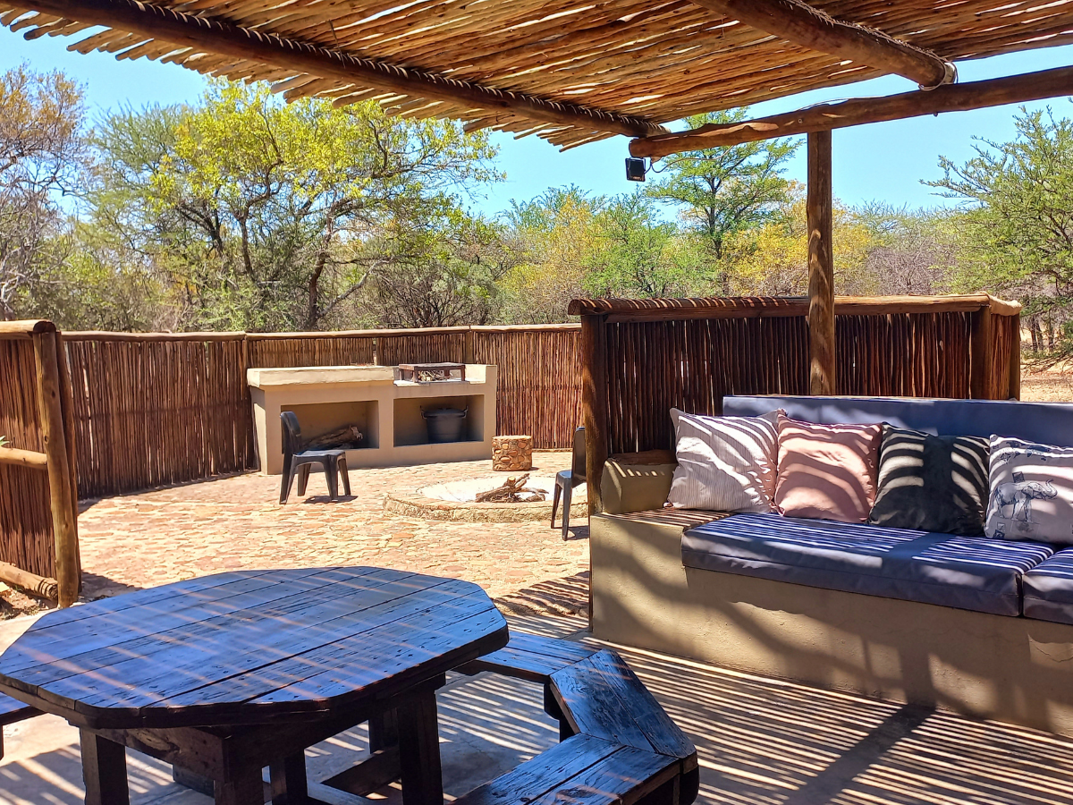 Rock Cottage covered patio with outdoor seating and private boma/braai at Sun Acres Farm